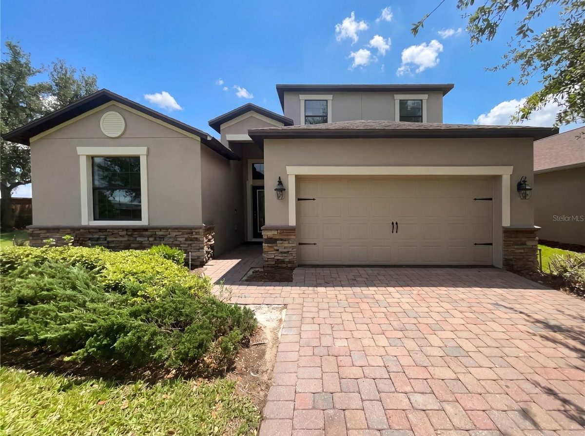 2200 Romanum Drive, a two-story stucco home with a stone accent and paver driveway in Alexander Ridge, Winter Garden